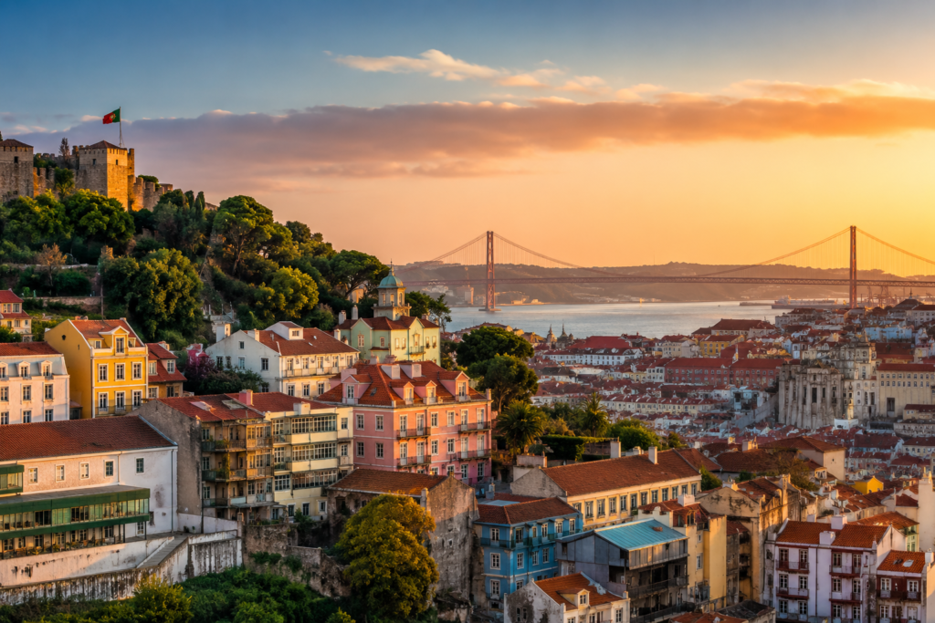 Vista panorâmica de Lisboa ao entardecer, com suas tradicionais construções coloridas, ruas históricas e o rio Tejo ao fundo.